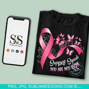 Op de afbeelding: Een zwart T-shirt met een roze lint en vlinders. De tekst "Support Squad You Are Not Alone" staat op het T-shirt gedrukt.