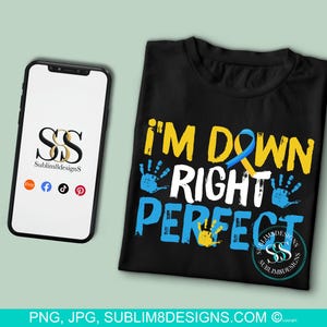 May include: Black t-shirt with the text "I'm Down Right Perfect" in white paint with blue and yellow handprints and a blue ribbon. The text "Sublim8Designs" is in the bottom right corner.