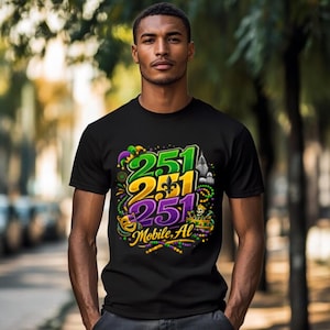 Puede incluir: Camiseta negra con un diseño gráfico colorido. El diseño presenta los números "251" en verde, amarillo y morado, junto con las palabras "Mobile, AL". El diseño incorpora elementos del Mardi Gras como cuentas y una máscara.