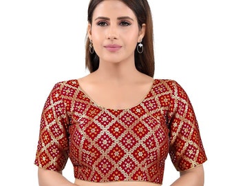 May include: A red, short-sleeved blouse with a geometric pattern in gold and white. The blouse has a round neckline and is made of a soft, silky fabric.