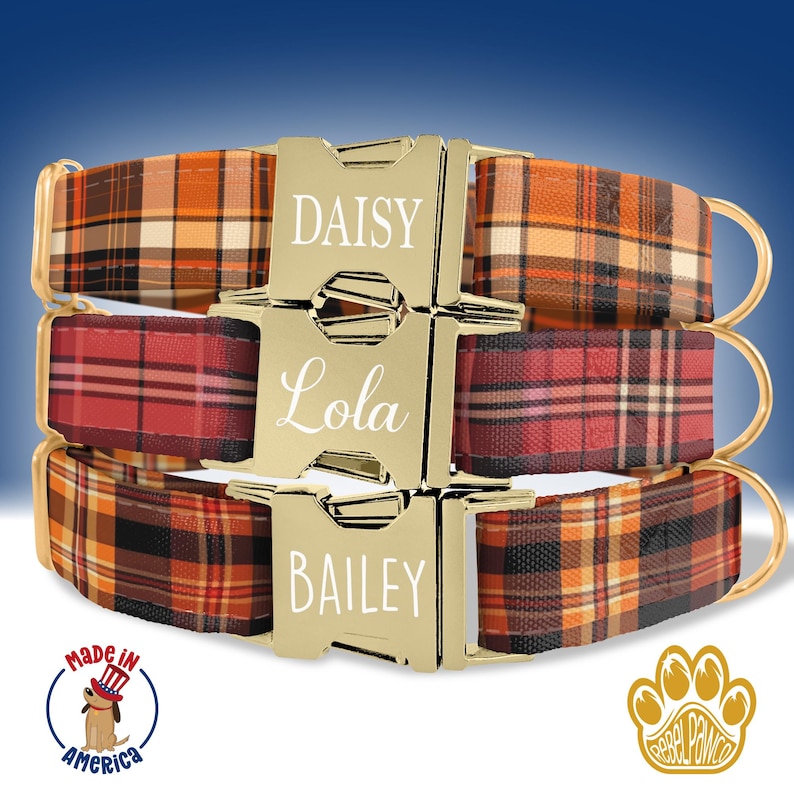 May include: Three plaid dog collars in shades of orange, red, and brown. The gold-colored buckles are engraved with the names "Daisy", "Lola", and "Bailey". The collars have gold-colored metal hardware. The image includes a "Made in America" logo.