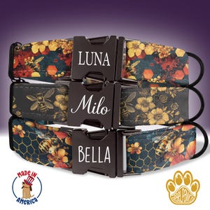 May include: Three dog collars featuring a floral and bee design. The collars are black with yellow, orange, and red flowers and bees. The collars have silver buckles with the names "Luna", "Milo", and "Bella" engraved on them.
