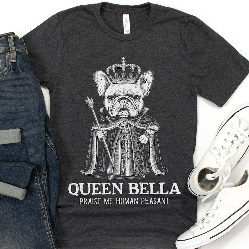 Puede incluir: Una camiseta gris oscuro con un gr&aacute;fico blanco de un bulldog franc&eacute;s con una corona y una t&uacute;nica. El texto "Queen Bella" y "Praise me human peasant" est&aacute; impreso debajo del gr&aacute;fico.