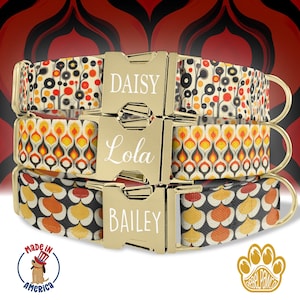 May include: Three dog collars with different patterns and personalized names: Daisy, Lola, and Bailey. The collars are made of white fabric with black and orange geometric designs. The collars have gold buckles with white lettering.