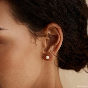 Może przedstawiać: Zbliżenie na ucho z małym, białym kolczykiem z pereł.