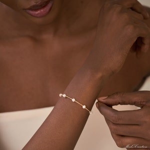 May include: A delicate gold bracelet with small white pearls. The bracelet is simple and elegant, perfect for everyday wear.