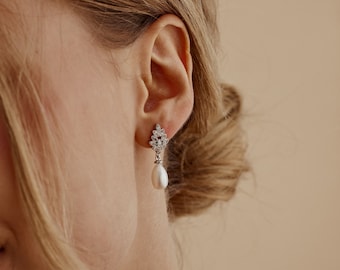 May include: Silver dangle earrings with a pearl drop and a cluster of clear cubic zirconia stones.