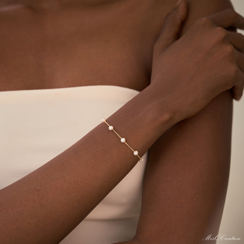 May include: A delicate gold chain bracelet with small white pearls. The bracelet is simple and elegant, perfect for everyday wear.