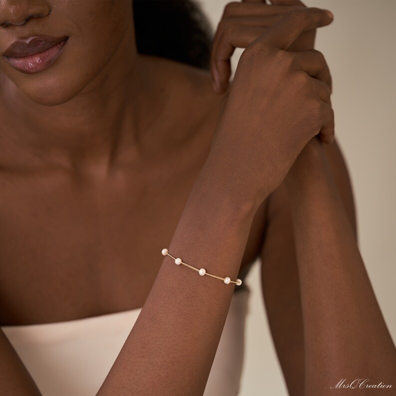 May include: A delicate gold chain bracelet with small white pearls. The bracelet is simple and elegant, perfect for everyday wear.