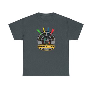 Puede incluir: Camiseta gris oscuro con un gráfico colorido. El gráfico incluye un diseño circular con vista de cabina, guitarras y el texto "SUMMER TOUR A WAVE OF HOPE EPISODE XL". El diseño tiene acentos amarillos, verdes, azules y rojos.