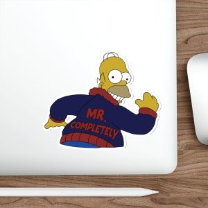 Puede incluir: Una pegatina con Homer Simpson de la serie de dibujos animados Los Simpson. Homer lleva una chaqueta azul con las palabras "MR. COMPLETELY" en rojo. La pegatina está sobre una superficie blanca.