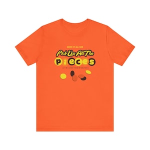 May include: Orange t-shirt with the text "Pick Up All The Pieces" in a playful font, with the word "pieces" in yellow. The shirt also has the text "Know It All Size" and "Let Me Learn From My Mistakes".