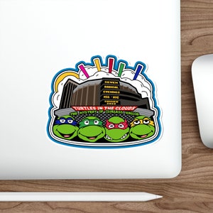 Puede incluir: Una pegatina con las Tortugas Ninja con el texto "Turtles in the Clouds" y "The Mystery of Clueless Wallob". El diseño incluye un edificio y las palabras "Seven Radical Evenings, MSG - NYC, Summer 2023."