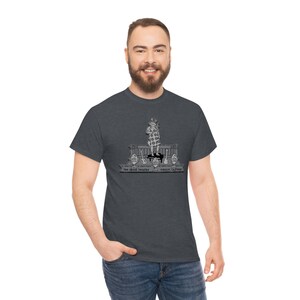 Puede incluir: Camiseta gris oscuro con una ilustración en blanco y negro de una persona en un escenario con guitarras. El texto de la camiseta dice "The Greek Theatre" y "Berkeley, California".