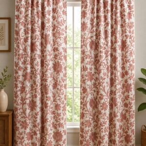 Peut inclure: Deux rideaux de fenêtre pleine longueur présentant un fond blanc avec un motif floral et végétal répétitif de couleur terre cuite. Les rideaux sont suspendus à une tringle en métal brun foncé et ont une tête froncée avec un passe-tringle.