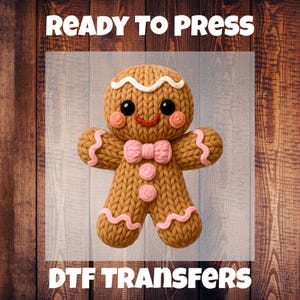 Peut inclure: Transfert DTF d'un bonhomme en pain d'épices marron avec un nœud papillon, des boutons et des accents roses. Les textes "READY TO PRESS" et "DTF TRANSFERS" sont affichés au-dessus et en dessous.