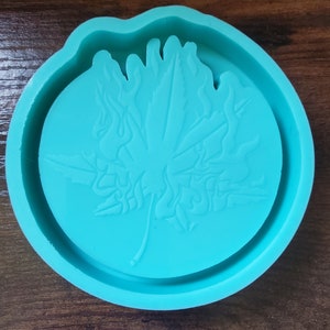 May include: A teal blue silicone mold shaped like a leaf with a raised design. The mold is perfect for creating resin crafts.
