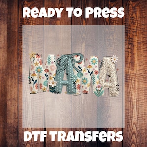 May include: A DTF transfer with the word "MAMA" in a floral design. The letters are decorated with flowers, bows, and animal print. The text "READY TO PRESS" and "DTF TRANSFERS" are above and below the design.