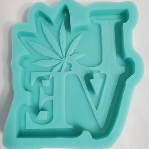 May include: A teal blue silicone mold shaped like the word "LOVE" with a marijuana leaf design in the "O".