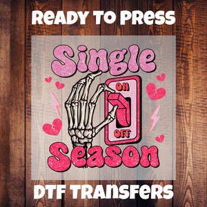 May include: A DTF transfer with the text "READY TO PRESS" at the top and "DTF TRANSFERS" at the bottom. The design features the words "Single Season" in pink glitter font, a skeleton hand flipping a switch from "ON" to "OFF", and pink hearts and lightning bolts.