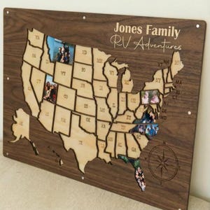 May include: Wooden map of the United States with state outlines and photo inserts. The map is mounted on a dark wood background. Text reads "Jones Family RV Adventures" and a compass rose is etched on the lower right.