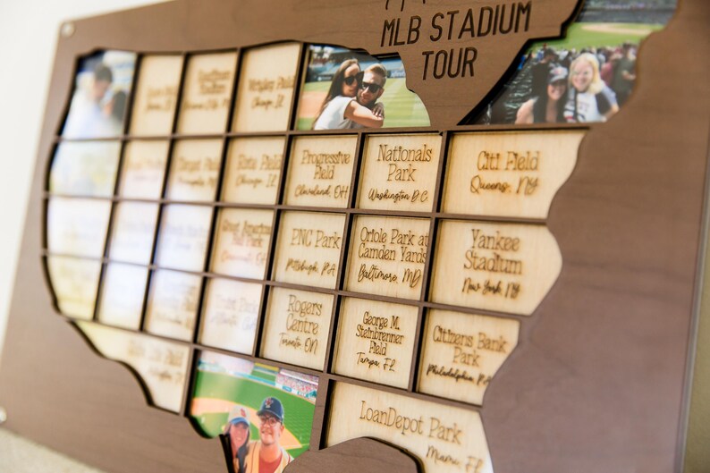 May include: Wooden MLB Stadium Tour map with individual photo slots. The map is shaped like the United States and features engraved stadium names. Photos are inserted into the slots, creating a personalized travel memory display.