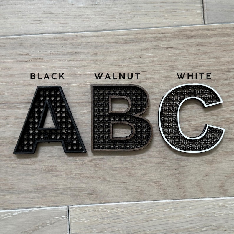 K&ouml;nnte beinhalten: Drei Holzbuchstaben, A, B und C, in Schwarz, Walnuss und Wei&szlig;. Die Buchstaben werden auf einer hellen Holzoberfl&auml;che angezeigt. Das Wort "BLACK" steht &uuml;ber dem Buchstaben A, "WALNUT" &uuml;ber B und "WHITE" &uuml;ber C.