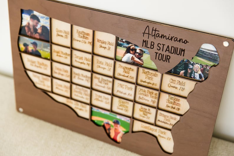 May include: Wooden map of the United States with cutouts for photos, labeled "Attamirano MLB Stadium Tour." The map features small wooden plaques with baseball stadium names and photos inserted into the cutouts. The wood is a medium brown color.
