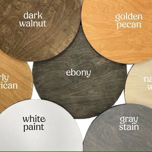 May include: Six round wooden samples in different wood stains and paint colors. The samples are labeled "dark walnut", "golden pecan", "ebony", "natural wood", "white paint", and "gray stain".