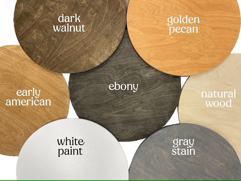 May include: Six round wooden samples in different wood stains and paint colors. The samples are labeled "dark walnut", "golden pecan", "ebony", "natural wood", "white paint", and "gray stain".