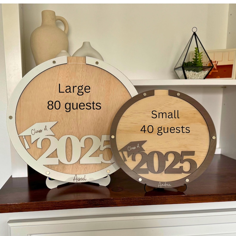 May include: Two wooden graduation guest book alternatives. The large one is white with the text "Large 80 guests" and "Class of 2025". The small one is brown with the text "Small 40 guests" and "Class of 2025".