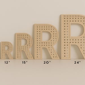K&ouml;nnte beinhalten: F&uuml;nf Holzdekorationen in Form des Buchstabens "R" in verschiedenen Gr&ouml;&szlig;en, von 17,8 cm bis 61 cm, mit einem gewebten Rohrdesign in der Mitte. Die Buchstaben sind hellbraun vor neutralem Hintergrund.