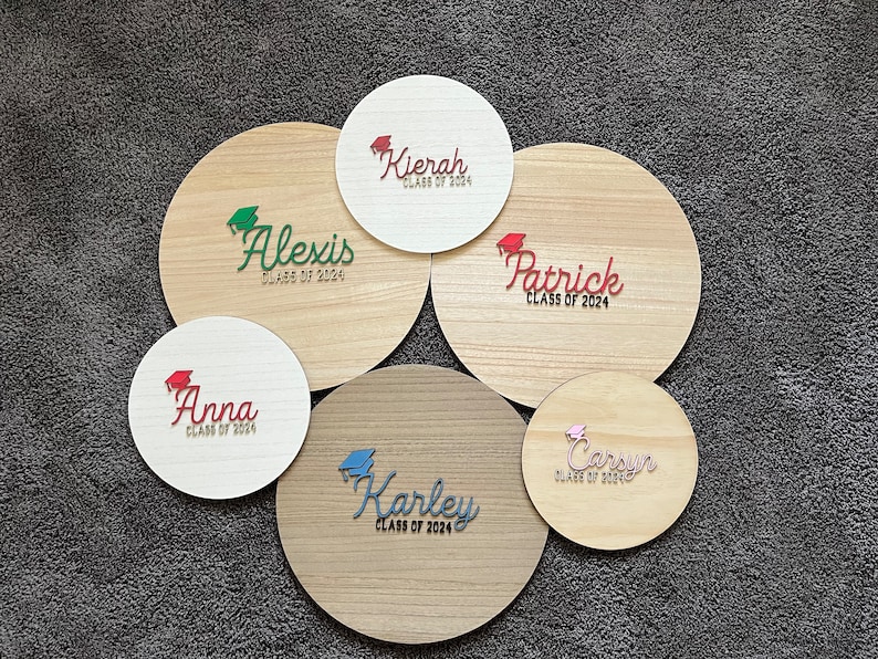 May include: Six round wooden signs with the names Alexis, Kierah, Anna, Karley, Patrick, and Carsun, each with the text "Class of 2024" and a graduation cap graphic.