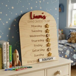 Puede incluir: Tabla de buenas elecciones de madera con el nombre "Liam's" en escritura roja. La tabla tiene d&iacute;as de la semana, iconos de estrellas y caras sonrientes, y una secci&oacute;n de "Recompensa" con la palabra "SQUISHY".