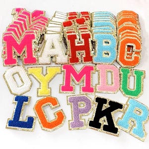 May include: Assortment of colorful felt letter patches with gold glitter trim. The letters include A, B, C, D, H, K, L, M, O, P, R, U, and Y.