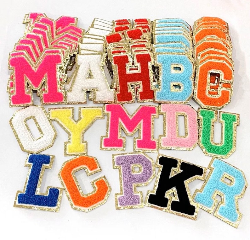 May include: Assortment of colorful felt letter patches with gold glitter trim. The letters include A, B, C, D, H, K, L, M, O, P, R, U, and Y.