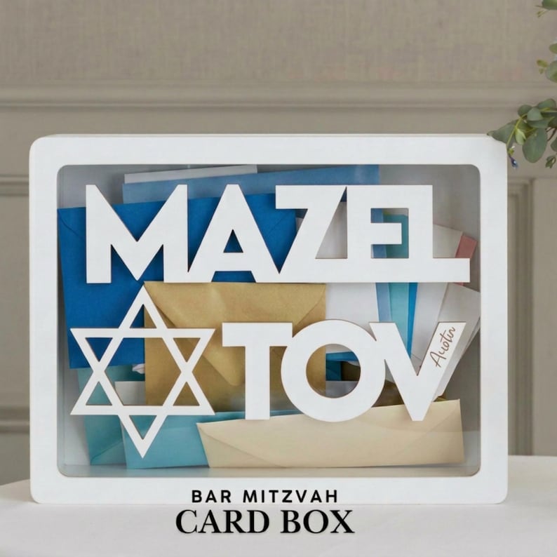 White card box with clear front panel, displaying the words "MAZEL TOV" and a Star of David, with the name "Austin". The box is filled with colorful cards. The top of the box reads "BAR MITZVAH CARD BOX".