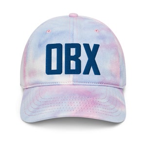 May include: A blue and pink tie-dye baseball cap with the text "OBX" embroidered in navy blue.