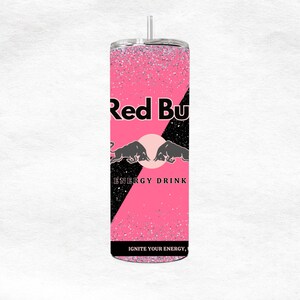 May include: A pink glitter tumbler with the Red Bull logo. The tumbler features the words "Red Bull" in black, along with the brand's bull logo and the words "ENERGY DRINK". The text "IGNITE YOUR ENERGY" is also visible.