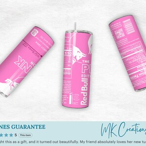 May include: Three pink Red Bull tumblers are displayed against a white background. The tumblers feature the Red Bull logo and text, including "The Pink Edition" and "Wild Berries." Each tumbler has a straw and a nutrition facts label.