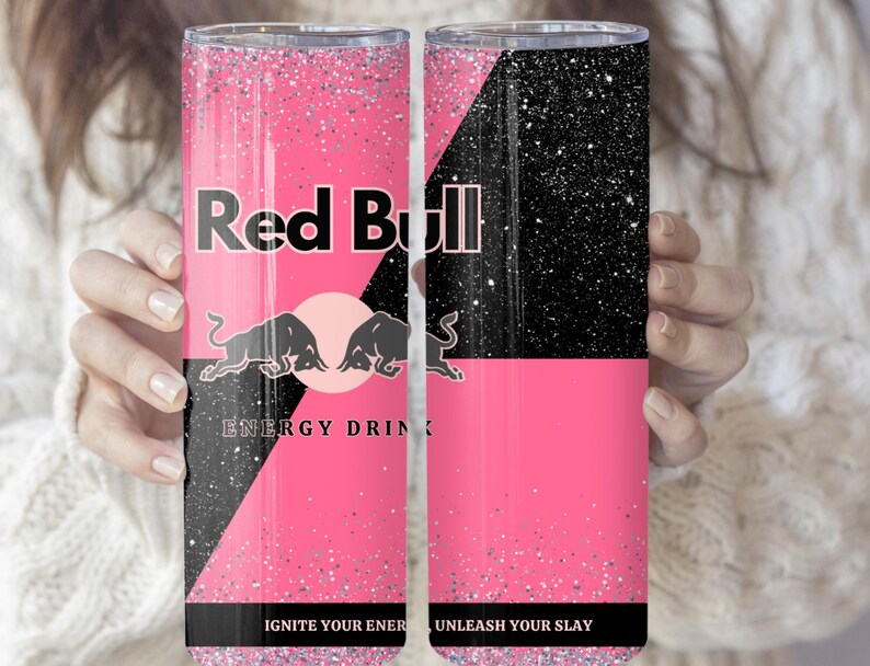 May include: A pink and black tumbler featuring the Red Bull logo with two bulls and the words "ENERGY DRINK". The tumbler has a glittery finish and the text "IGNITE YOUR ENERGY" and "UNLEASH YOUR SLAY".