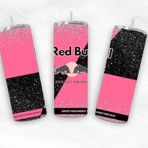 May include: Three pink and black glitter tumblers with a silver straw. The tumblers feature the Red Bull logo and the phrases "NAUGHTY BITCH ENERGY", "IGNITE YOUR ENERGY", and "LEASH YOUR SLAY".