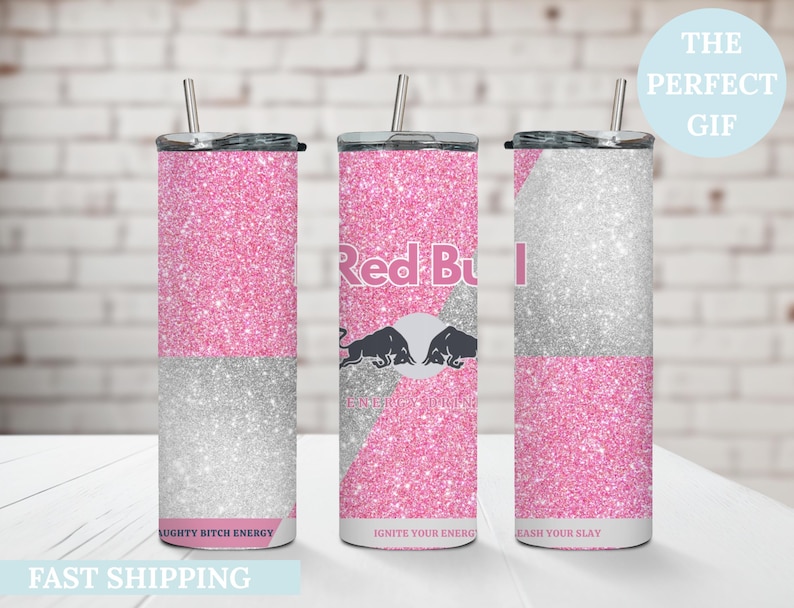 May include: Three glitter-covered tumblers with straws. The tumblers are pink and silver, with the Red Bull logo on one. Text on the tumblers reads "NAUGHTY BITCH ENERGY", "IGNITE YOUR ENERGY", and "UNLEASH YOUR SLAY".