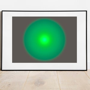 Op de afbeelding: Een ingelijste abstracte kunstprint met een groene cirkel in het midden op een grijze achtergrond.