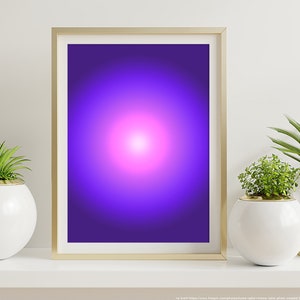Op de afbeelding: Een gouden ingelijst schilderij met een paarse en roze gradiënt achtergrond. Het schilderij staat op een witte plank met twee witte ronde potten met groene planten.