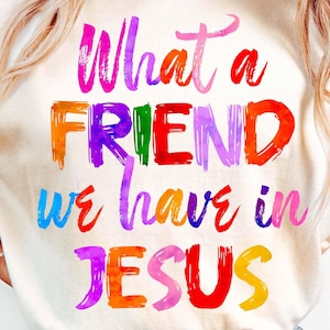 Może przedstawiać: Biała koszulka z napisem "What a friend we have in Jesus" napisanym kolorowymi literami, przypominającymi pociągnięcia pędzlem.