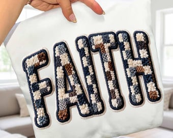 May include: White square pillow with the word "FAITH" embroidered in large, textured letters. The letters are filled with a plaid pattern in shades of blue, brown, and cream, outlined with a dark blue border.
