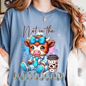 May include: A blue t-shirt with a cartoon cow wearing a blue bow and holding a cup of coffee. The text "Not in the Mooooood!" is printed on the shirt.