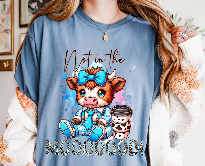 May include: A blue t-shirt with a cartoon cow wearing a blue bow and holding a cup of coffee. The text "Not in the Mooooood!" is printed on the shirt.