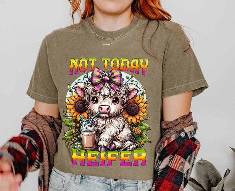May include: A brown t-shirt with a cartoon cow wearing a pink and yellow bow and drinking a milkshake. The text "Not Today Heifer" is printed on the shirt.